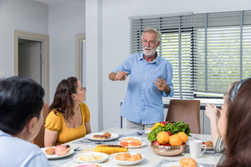 Happy family spend time having lunch or dinner on table together. Senior man enjoying while communicating with their family in dining room. Dad fun with family dinner together.	