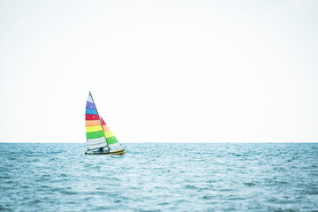 Naklejka premium Sailboat in the sea on white sky background.Luxury summer adventure and active vacation in the ocean.Sport sailboat sailing through a silver sea in a sunny day.