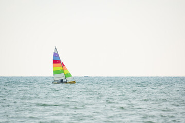 Fototapeta premium Sailboat in the sea on white sky background.Luxury summer adventure and active vacation in the ocean.Sport sailboat sailing through a silver sea in a sunny day.