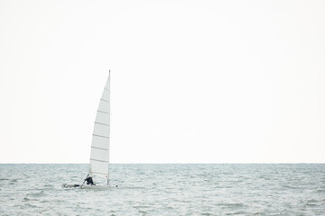 Obraz premium Sailboat in the sea on white sky background.Luxury summer adventure and active vacation in the ocean.Sport sailboat sailing through a silver sea in a sunny day.