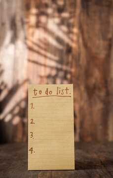 brown note paper to do list on wood wall and pencil box with sunlight