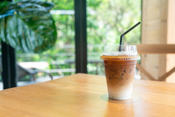 iced latte coffee in takeaway glass on table in coffee shop