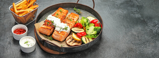 Salmon steak with vegetables on dark background.