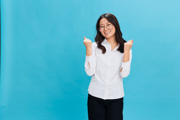 Overjoyed cute Asian businesswoman in round glasses classic office dress code celebrates successful...