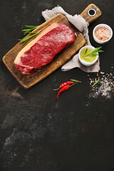 Raw striploin beef steak dark background.