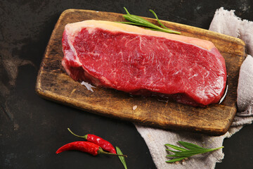 Raw striploin beef steak dark background.
