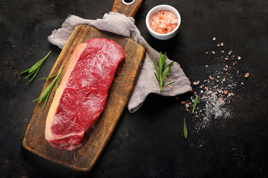 Raw striploin beef steak dark background.