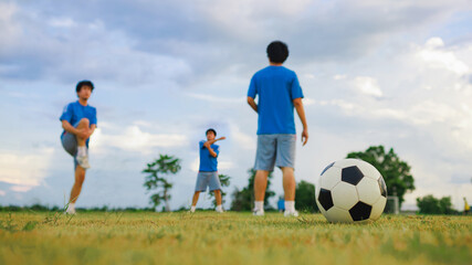 Fototapeta premium Action sport outdoors of kid having fun playing soccer football for exercise in community rural area under the twilight sunset sky.
