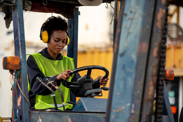 Young woman driving forklift in industrial container warehouse.