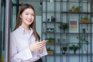 Asian professional working woman uses smartphone to chat with someone in digitalization and work from home concept.