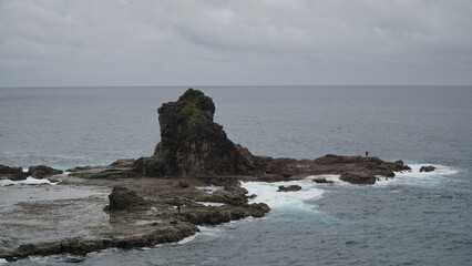 Coral rock on the beach and hit by the wave with cloudy sky.  Watu Lumbung Beach, Yogyakarta,...