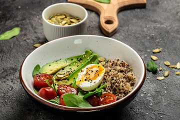 Keto diet plate quinoa, avocado, egg, tomatoes, spinach and sunflower seeds on dark background. Healthy food, ketogenic diet, diet lunch concept, place for text, top view