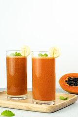 Orange papaya and banana smoothie mix on white background, copy space. A glass of fresh papaya and banana smoothie.