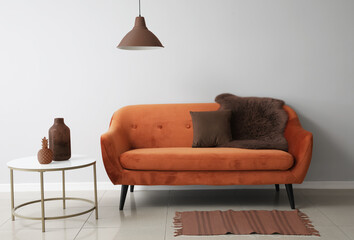 Stylish brown sofa and tabl near light wall