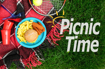Fast food with tennis racket on plaid in park. Picnic time
