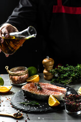 chef hands prepares fresh salmon steak fish, cooking with the addition of olive oil freezing in the air. Marinated salmon