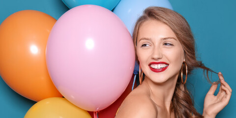 Fototapeta na wymiar Beautiful young woman with balloons on blue background