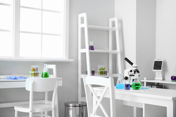 Modern workplace with microscope and chemical glassware in medical laboratory