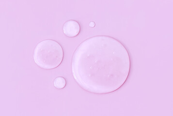 round drops of transparent gel serum on pink background