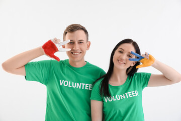 Volunteers with painted hands in colors of Ukrainian and Polish flags showing victory gesture on white background