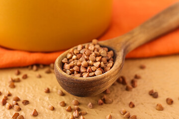 wooden spoon with buckwheat grains on table, closeup