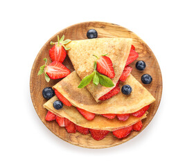 Plate of thin pancakes with strawberries and blueberries on white background