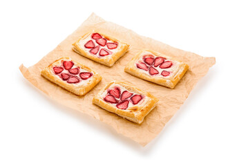 Parchment paper with strawberry puff pastries on white background