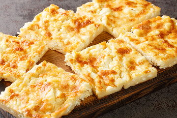 Greek traditional cheese pie with feta close-up on a wooden board on the table. horizontal