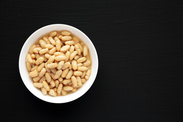 Organic White Cannellini Beans in a White Bowl, top view. Flat lay, overhead, from above. Copy space.