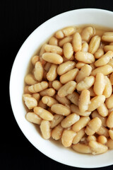 Organic White Cannellini Beans in a White Bowl, top view. Flat lay, overhead, from above. Close-up.
