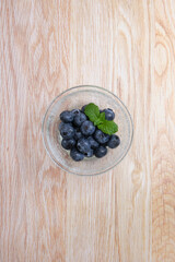 ガラスの器に盛られたブルーベリー、木目背景