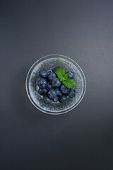 ガラスの器に盛られたブルーベリー、黒背景