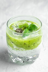 Healthy breakfast chia pudding with kiwi in glass jars on a white table. Clean eating, dieting, vegan food concept. vertical image