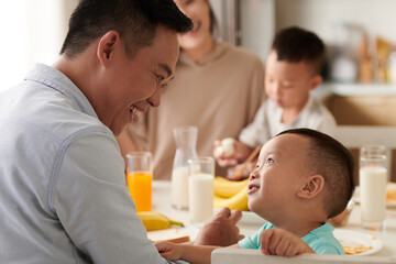 Smiling father and son talking during family breakfast