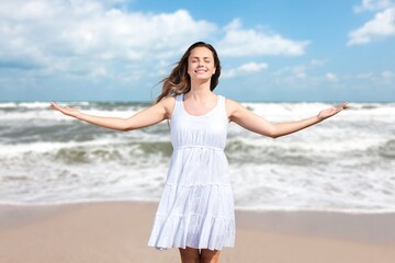 Fototapeta na wymiar Smiling woman relaxing on beach background. Happy woman standing on the sun beach