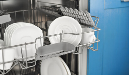 Dishwasher with white plates and cups on the kitchen