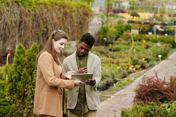 Young woman showing her house project on digital tablet to landscape designer while they buying...