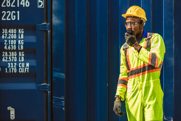 Black African male worker work as port cargo manager using radio control loading container in...