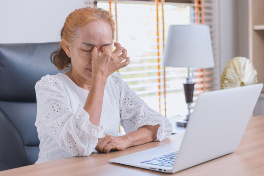 Woman elderly eyes pain from Asthenopia stress tired sinus suffer fatigue from hard work with computer screen.