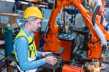 Worker man working with robot arm automate welding machine in modern metal factory. Engineer...