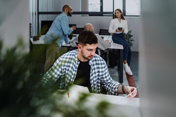 Portrait of young man sitting and working at his desk in the office.