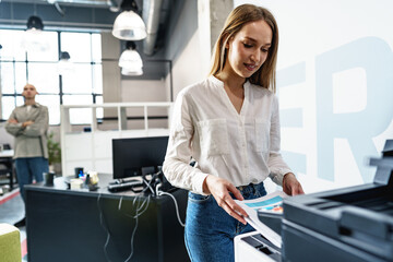 Young employee using modern printer in office