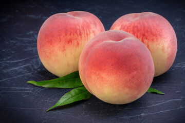 Fototapeta na wymiar Sweet Peach fruit with leaf on black wooden background, Fresh Sweet Peach on black wooden table.