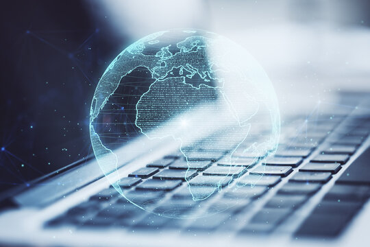Close up of laptop and creative glowing polygonal grid planet on blurry background. Globe, international map, communication, network earth and technology concept. Double exposure.