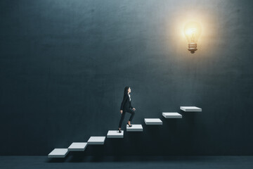 Fototapeta Way to success and creative idea concept with young woman climbing white stairs to big illuminated light bulb on dark grey wall obraz
