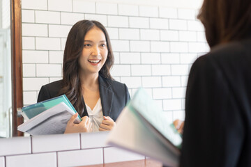 Confident, cheerful asian young woman standing in suit formal, practice talk with look in reflection mirror at toilet before job interview of change career, recruitment employee or staff in corporate.