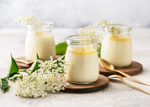 Homemade creamy elder flowers panna cotta with lemon sauce in vintage glass jars on a light concrete background. Desserts without baking. 