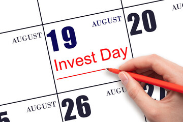 Hand drawing red line and writing the text Invest Day on calendar date August 19. Business and financial concept.