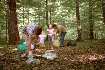 Naklejka na ściany i meble Ginger boy cleaning forest from trashes with family
