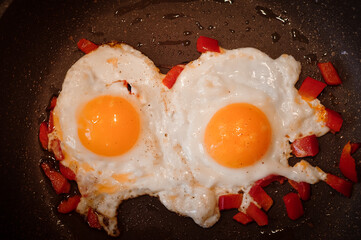 Two Fried eggs on pan with red pepper morning breakfast . High quality photo